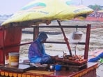 A local vendor keeps himself protected from the rain on Friday in Varanasi (Rajesh Kumar/HT)